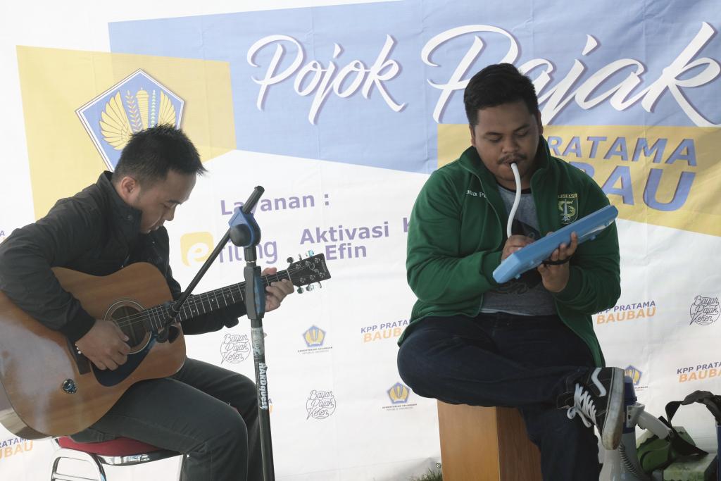 Dua orang petugas memberikan hiburan musik kepada pengunjung pojok pajak