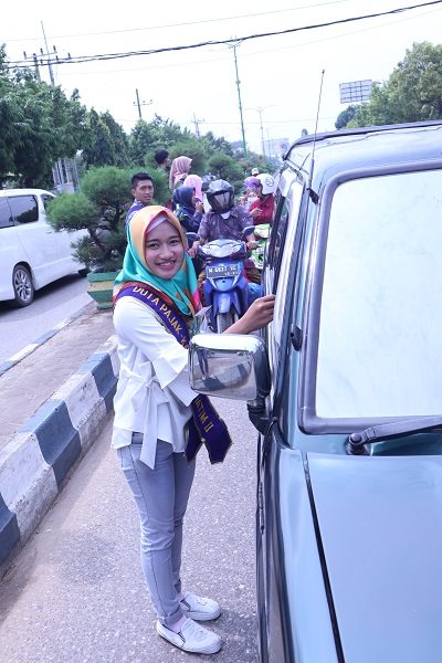 Salah satu Duta Pajak membagikan bunga kepada pengendara mobil