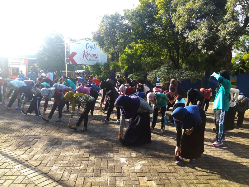 Ibu-ibu dan remaja putri melakukan pemanasan dan peregangan otot.