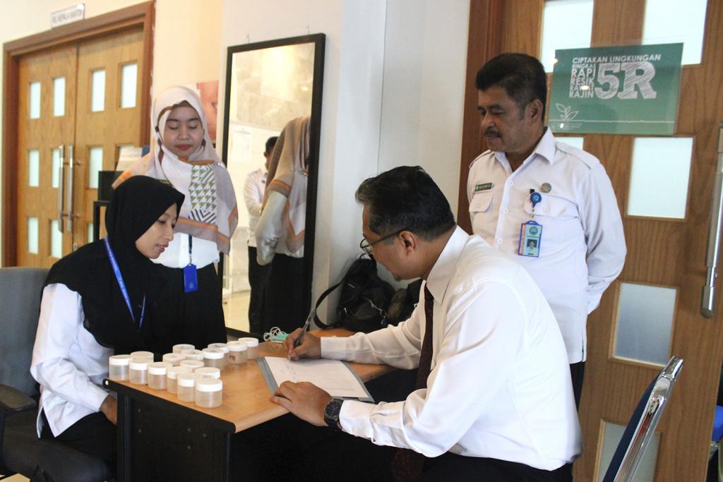 Kepala KPP Pratama Mamuju mengisi data dan mengambil wadah uji urin.