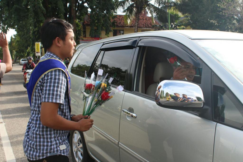 Salah satu Duta pajak mebagikan bunga kepada pengendara mobil